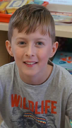 Boy of St. Aidans NS Ballintrillick with books behind him