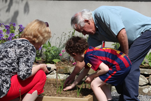 Noreen & Johnny Duignan helping children plant onions in garden of St Aidans NS Ballintrillick